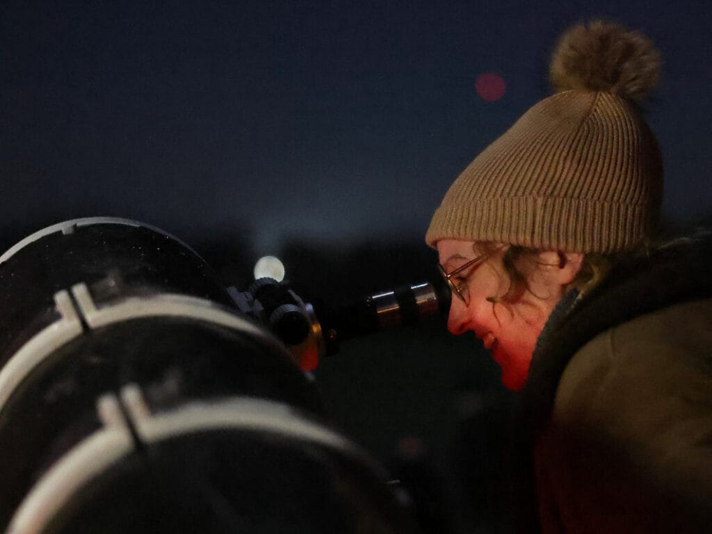 an adult looking through a telescope